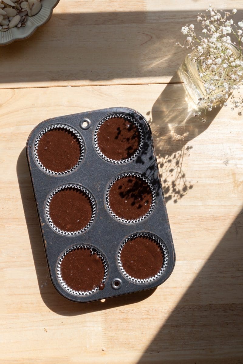 The filled cupcake liners in a 6-cavity muffin tin.