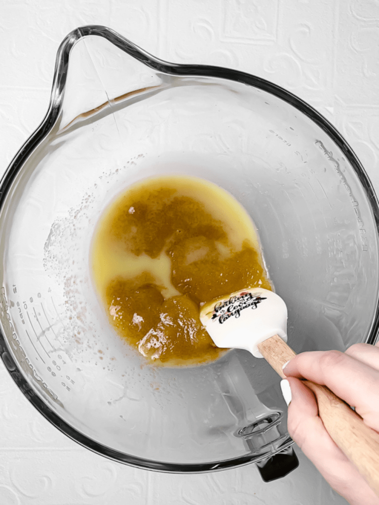 Mixing together the melted butter and both sugars in a large mixing bowl.
