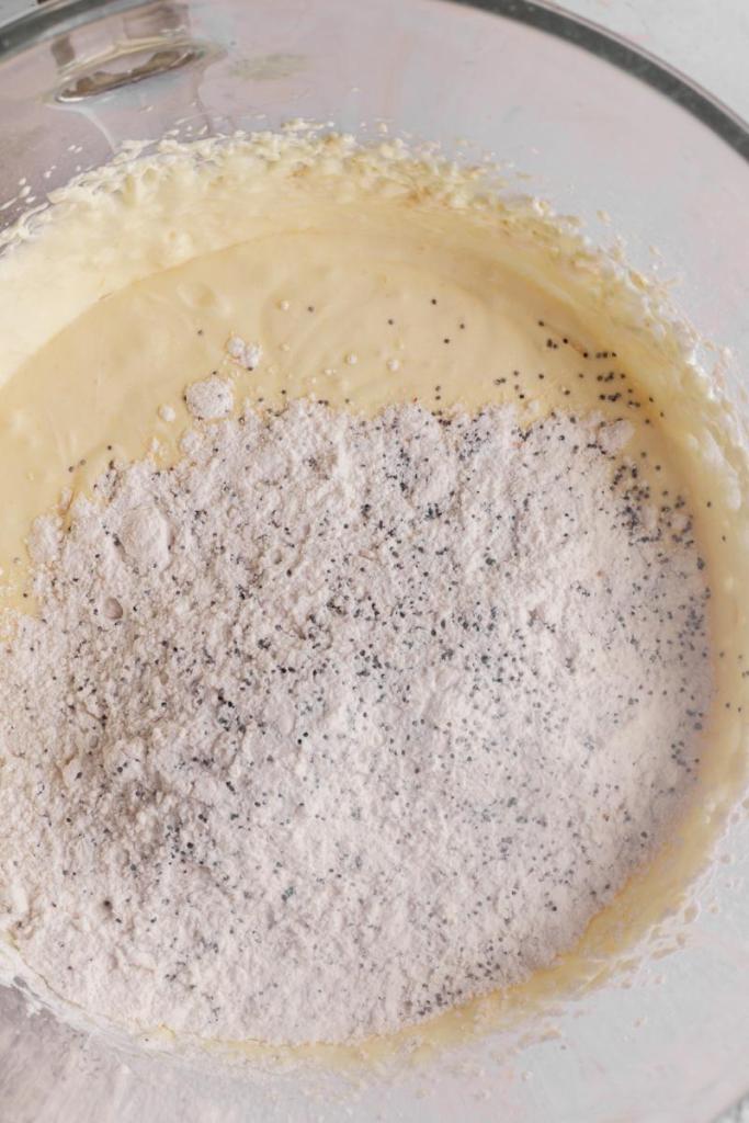 Dry ingredients with poppy seeds on top of the lemon poppy seed cake batter