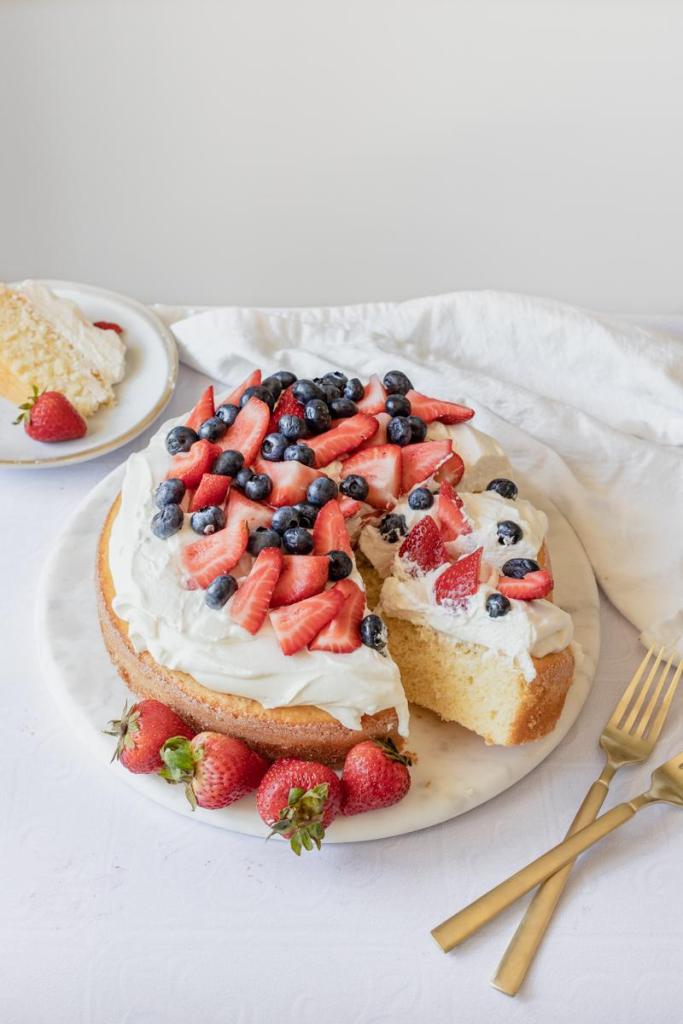 Picture of the berries and cream cake, a slice has been cut to show the inside.