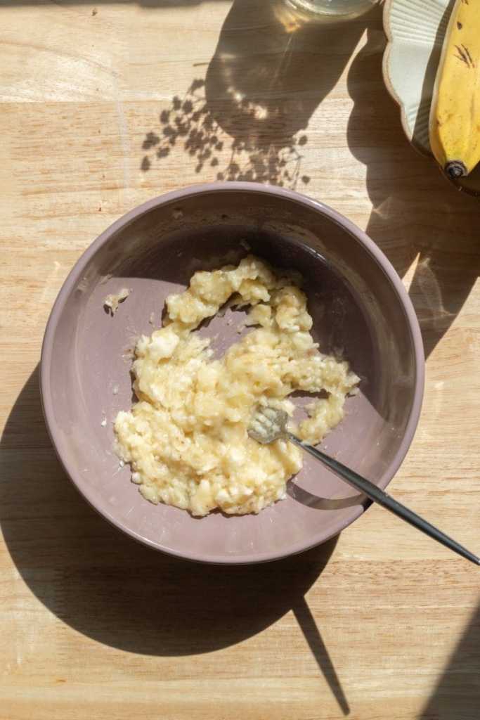 The banana mashed in a mixing bowl.