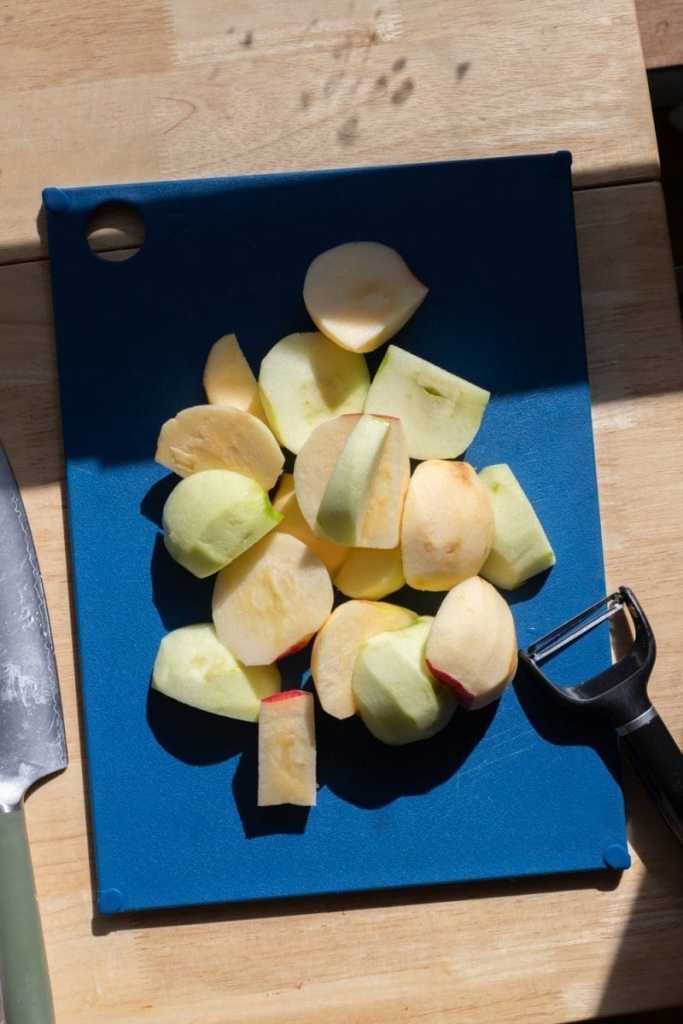 The peeled and cored apples on a cutting board.