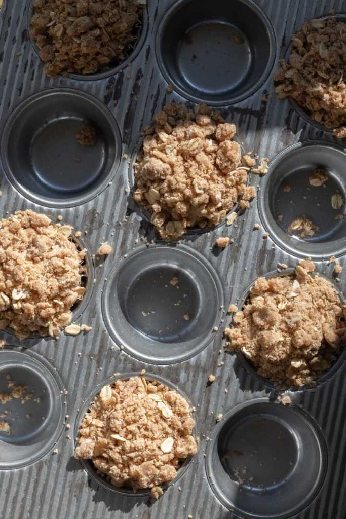 The muffin batter and streusel distributed between muffin liners.