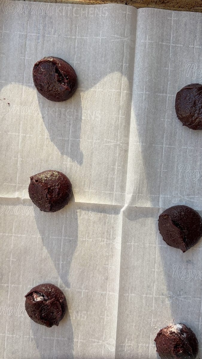 The scoops of cookie dough on a cookie sheet.