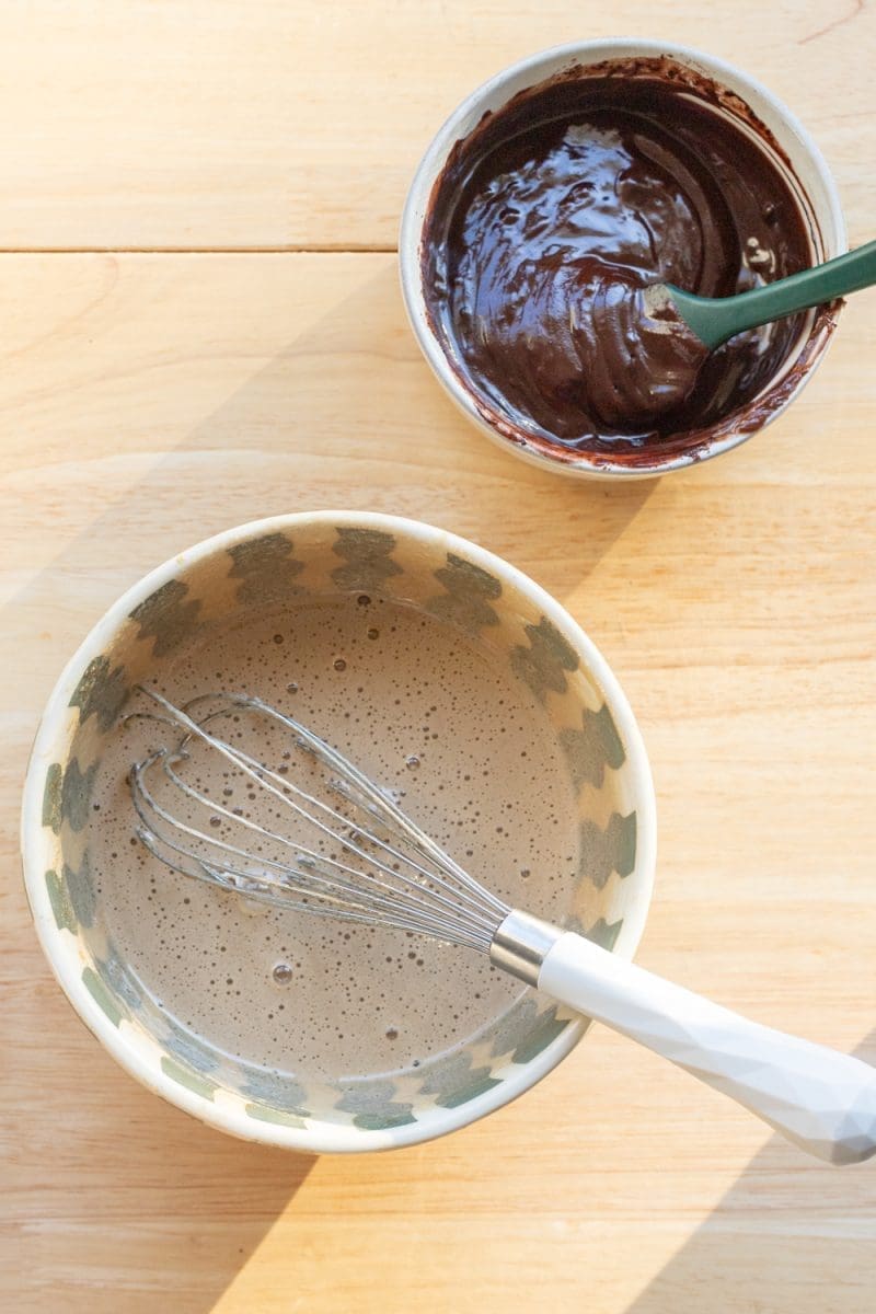 The eggs and sugar whisked together in a bowl, and the melted chocolate mixture in a bowl.