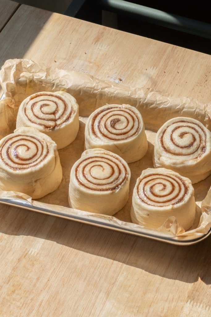 The six cinnamon rolls on a baking tray.