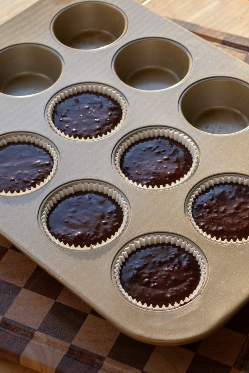 The cupcake batter distributed between six parchment liners.