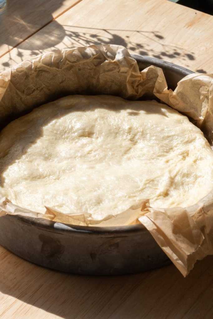 The brioche dough spread flat into a cake pan.
