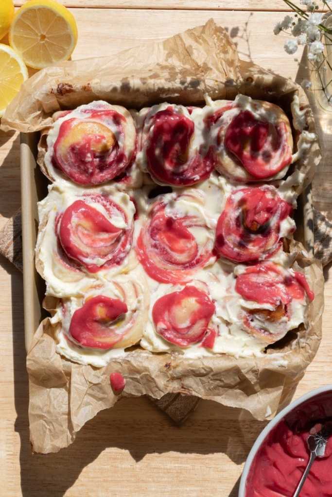 Overview of the frosted lemon raspberry rolls in a square pan.