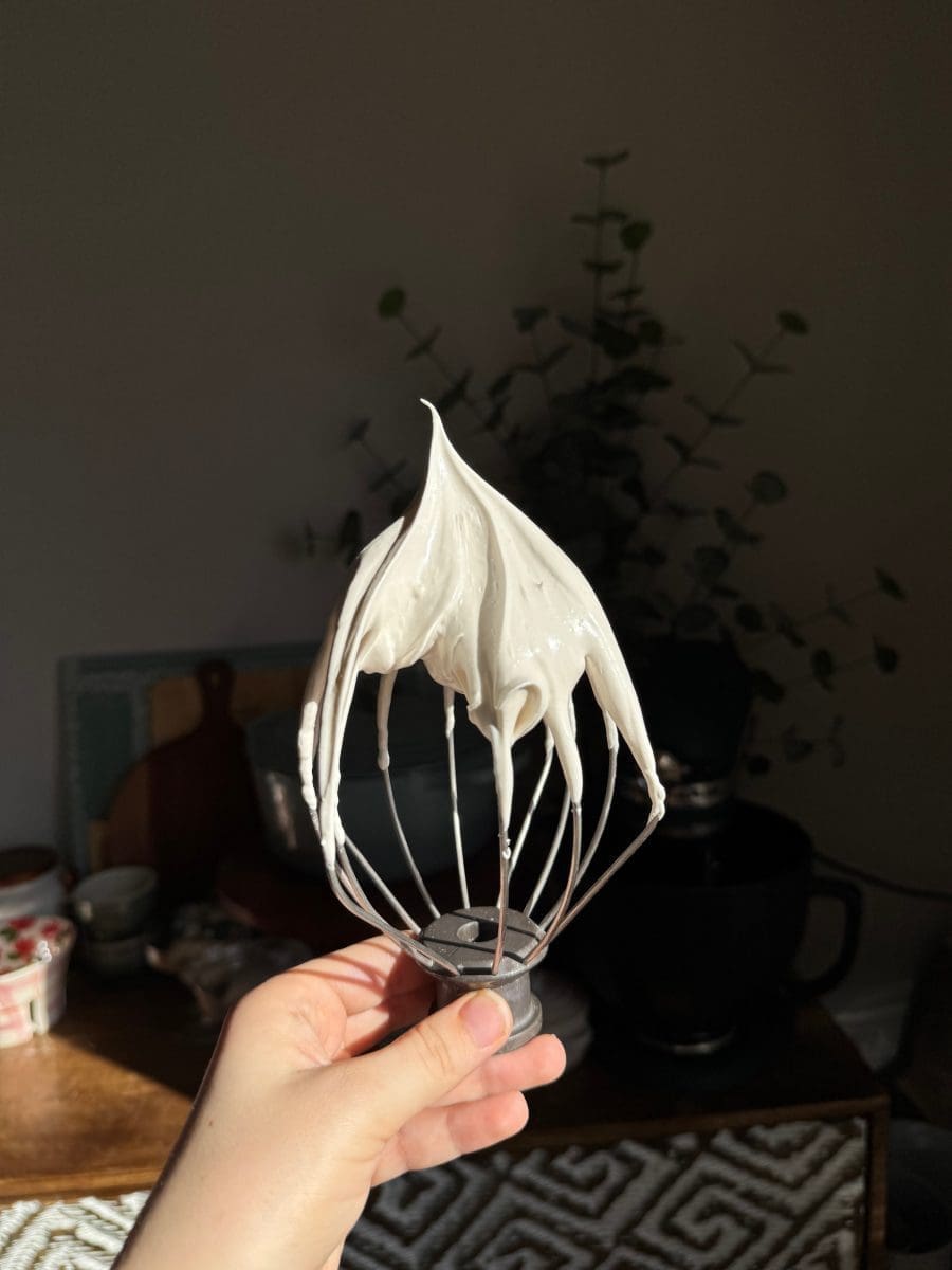 Holding up a whisk with meringue on it.