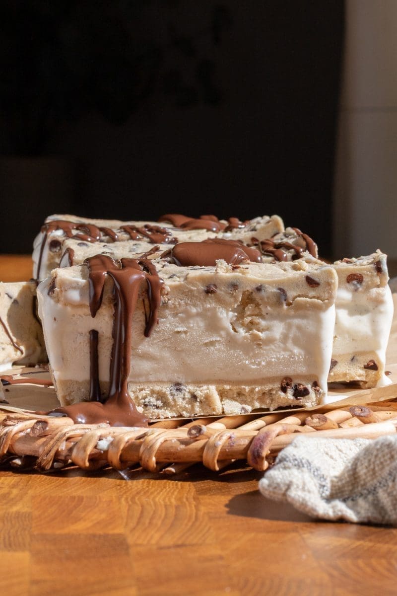 Close up of the cookie dough ice cream sandwiches with chocolate drizzled on them.