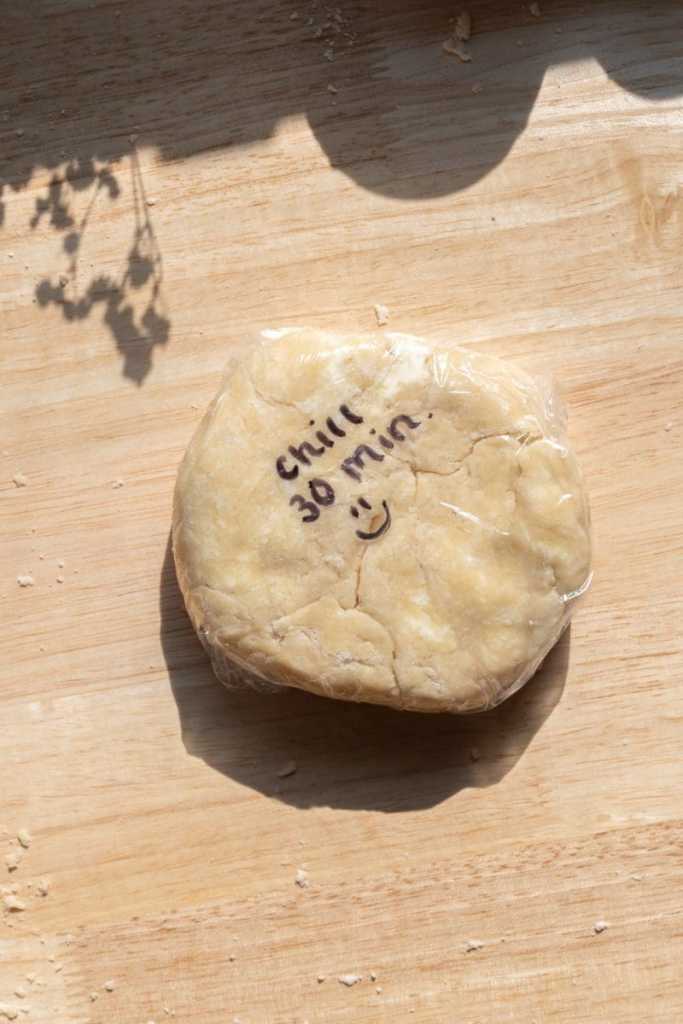 The pie crust wrapped up in plastic wrap with "chill 30 min. :)" written on it.