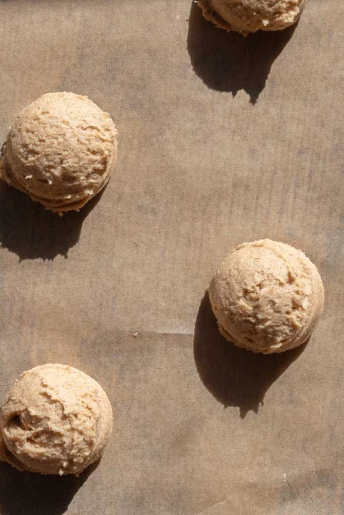 Cookie dough balls spaced out on a baking sheet.