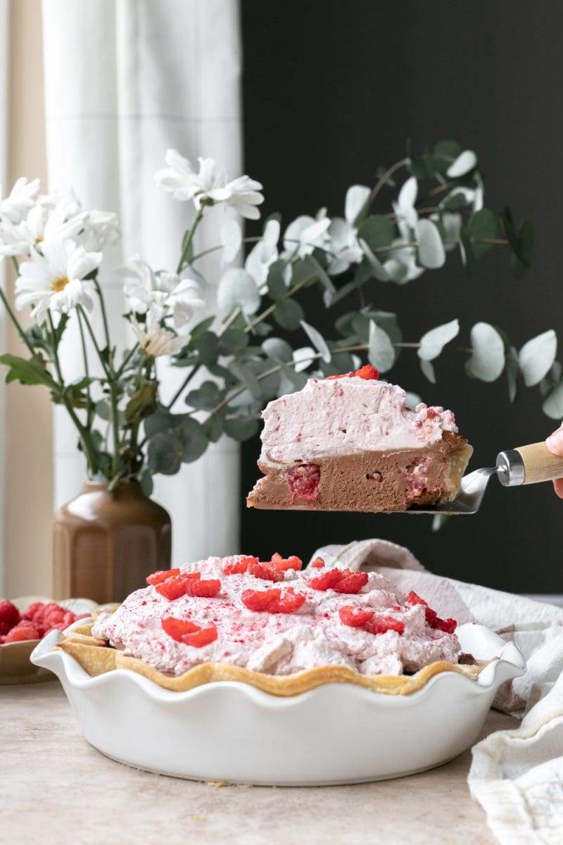 Holding up a slice of the raspberry mocha french silk pie over the pie.