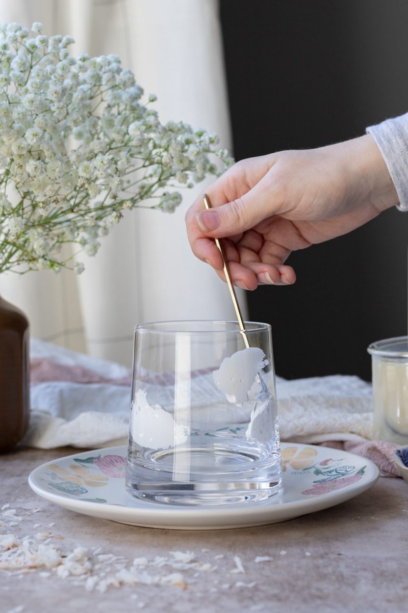 Using the back of a spoon to coat the inside of the cup with marshmallow fluff
