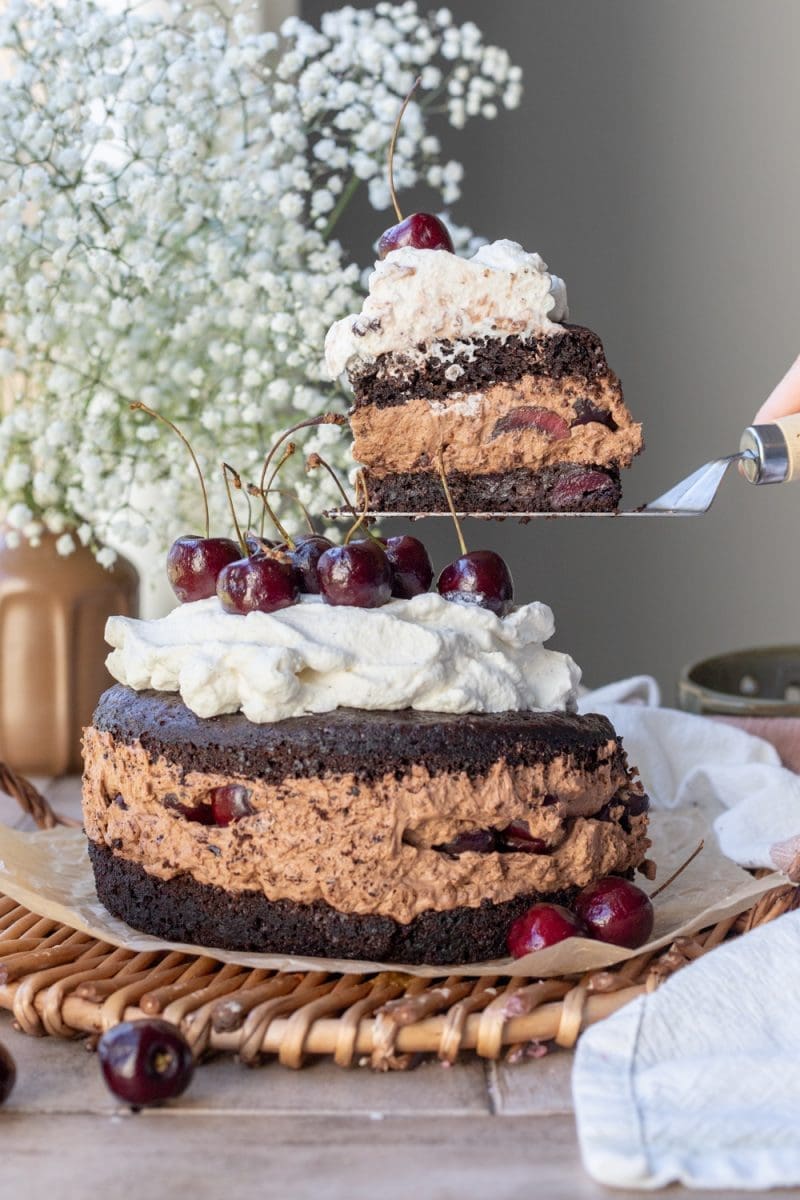Holding up a slice of the chocolate cherry cake over the whole cake
