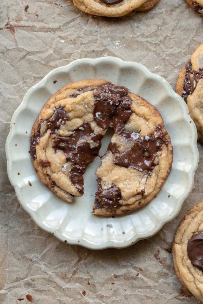A cookie broken in half on a tiny plate