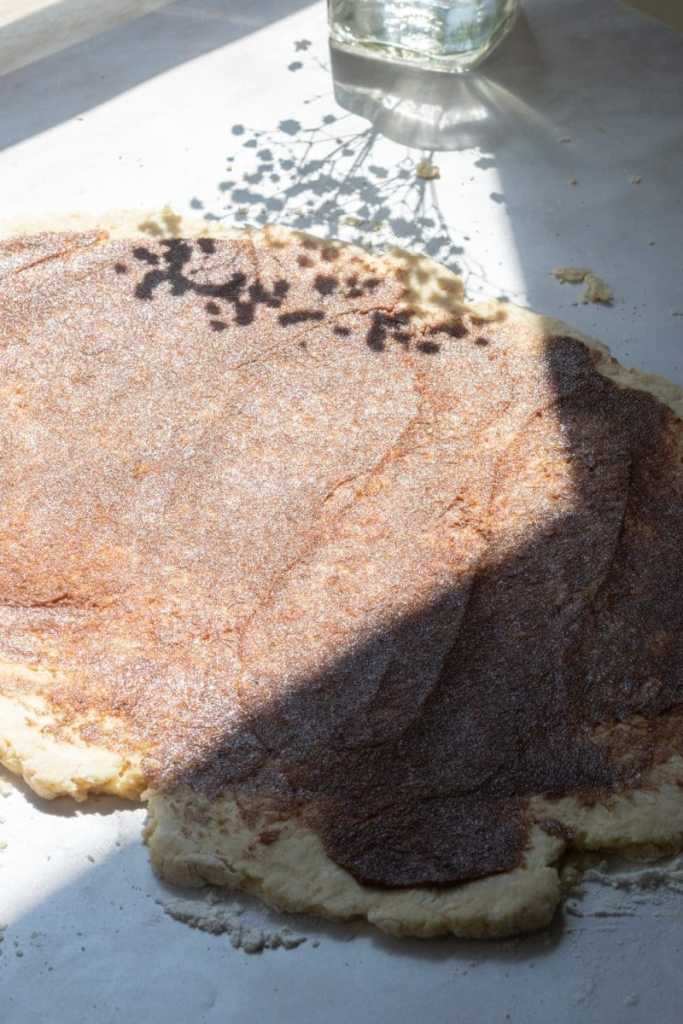 The rolled out scone dough with the cinnamon sugar filling spread over it.