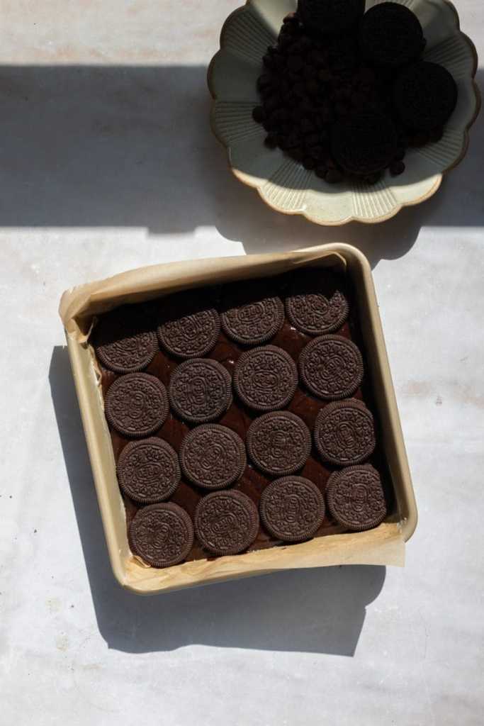 The brownie batter in a prepared baking dish with oreos pressed on top of it.