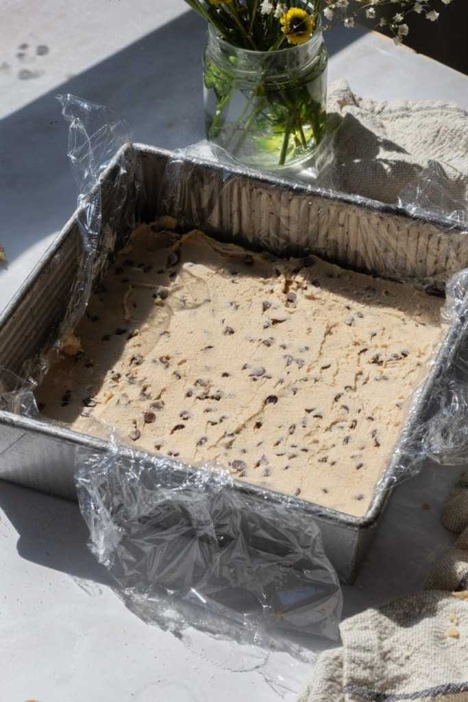 The cookie dough pressed down into a square pan.