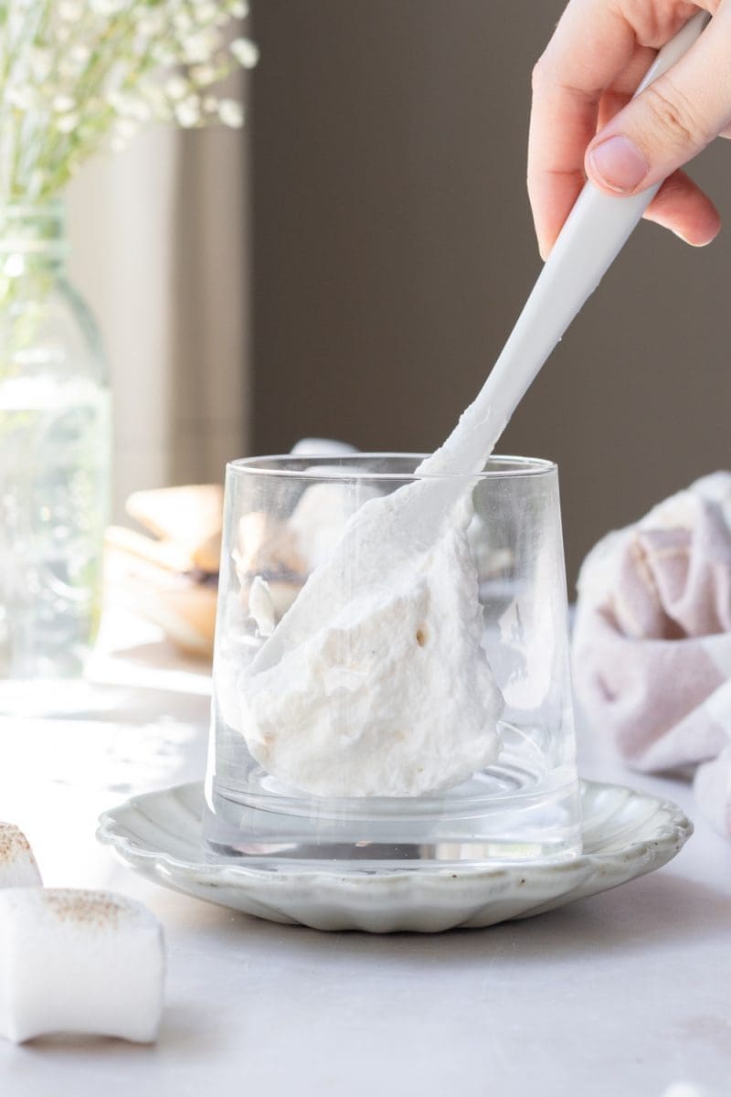 Placing toasted marshmallow whipped cream into the bottom of the cup.