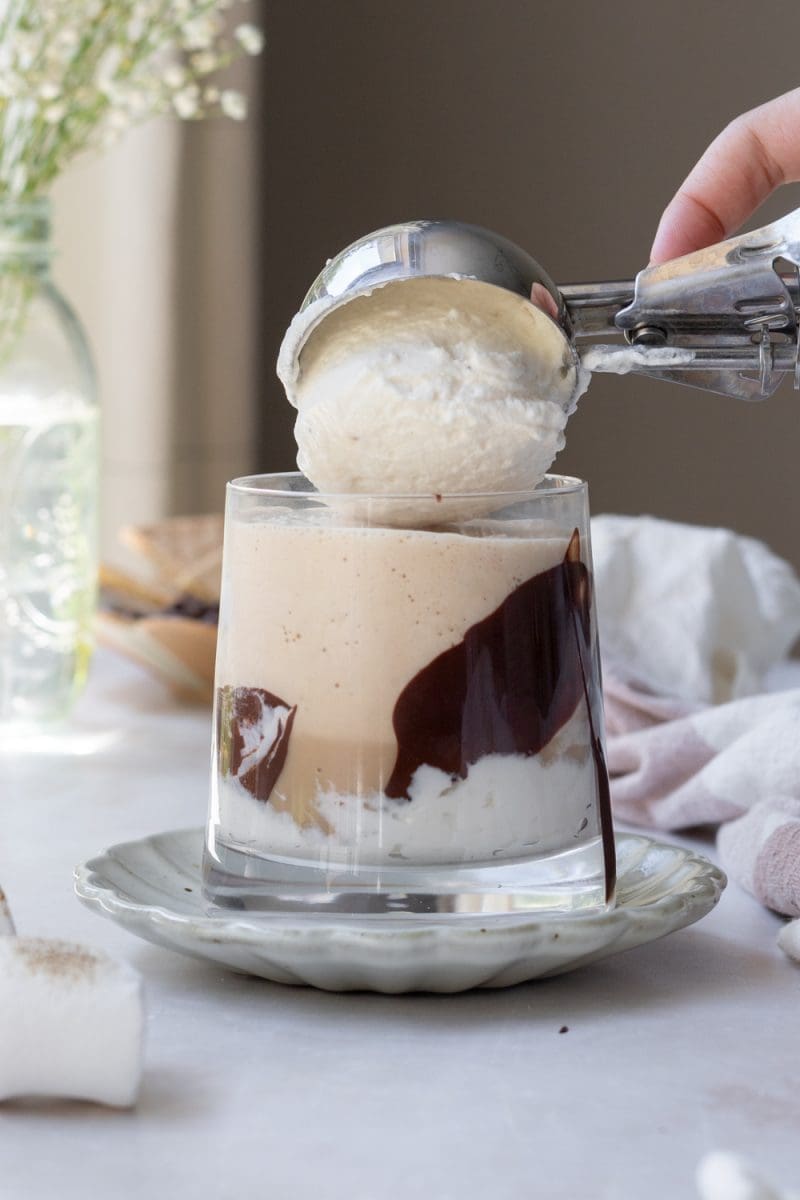 Placing a scoop of toasted marshmallow whipped cream on top of the drink.