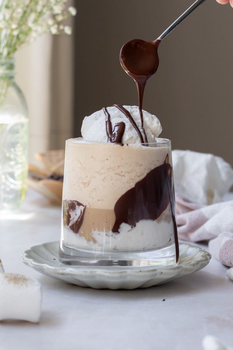 Drizzling chocolate sauce on top of the toasted s'mores frappuccino.