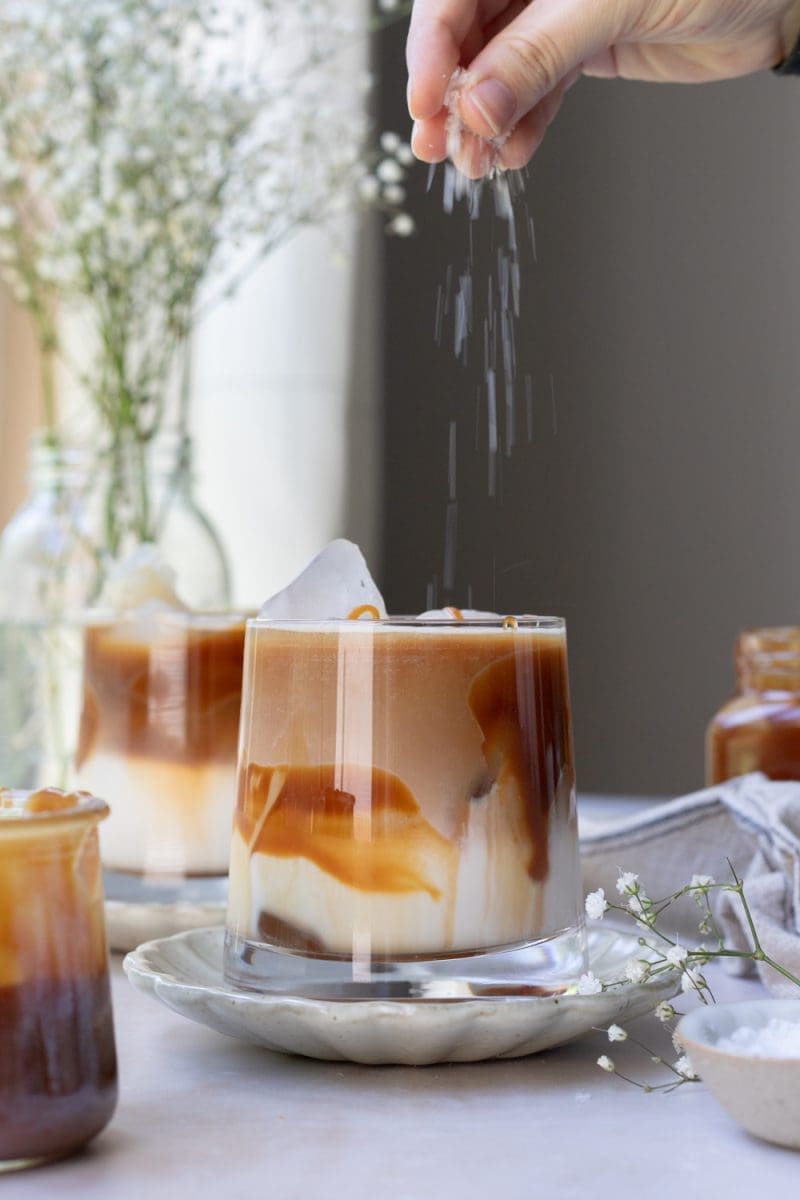 Sprinkling salt over the iced salted caramel macchiato