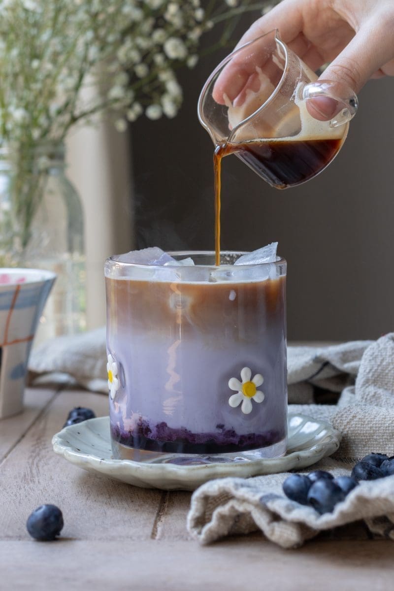 Pouring espresso over the iced blueberry latte.
