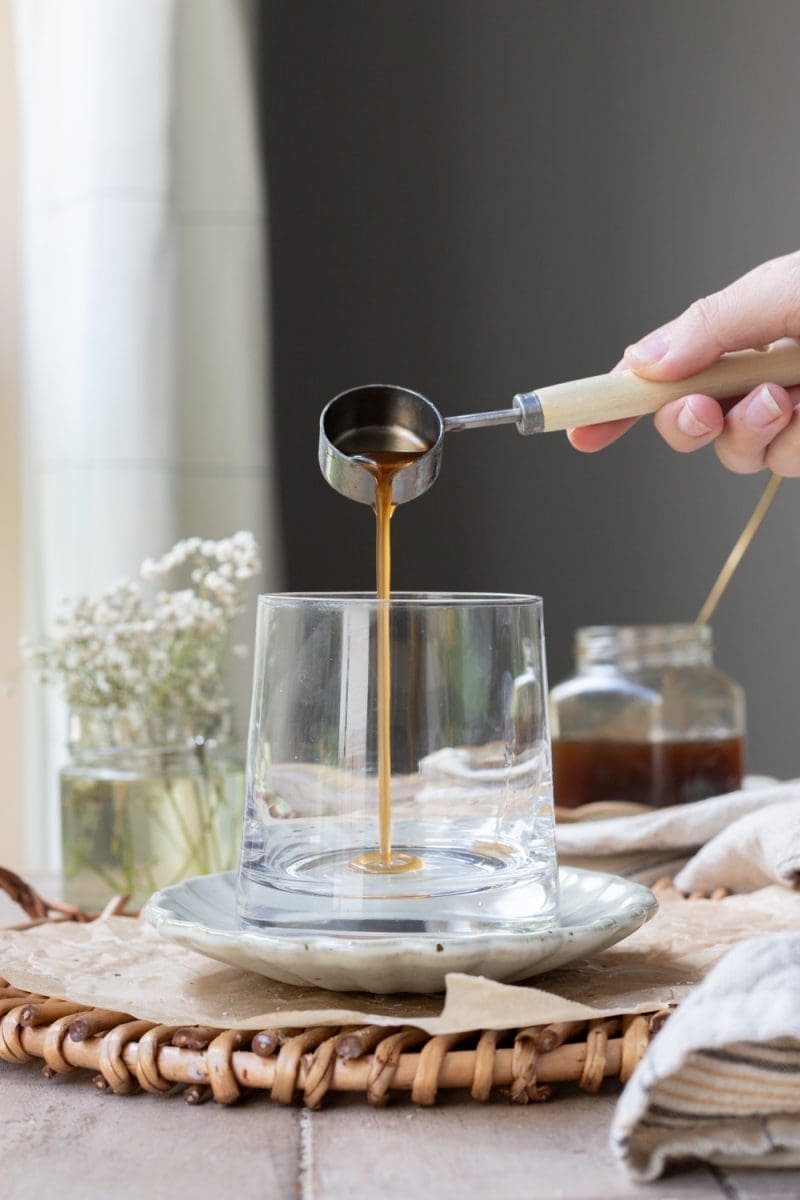 Pouring banana bread syrup into a cup.