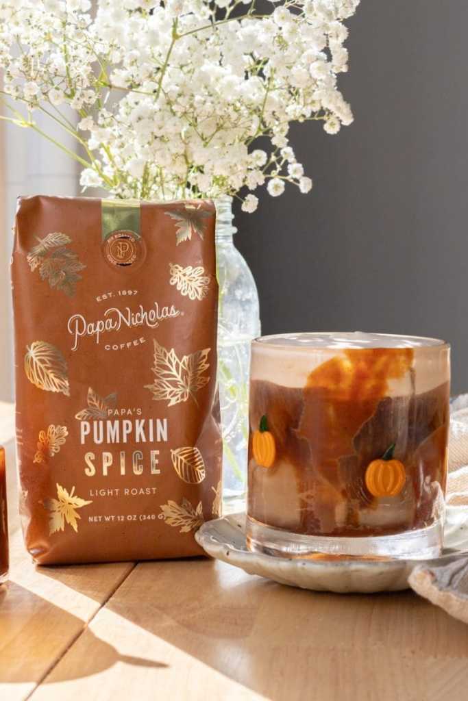 A pumpkin spice iced coffee next to a bag of coffee.