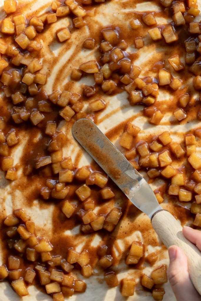 Spreading the apple pie filling over the dough.