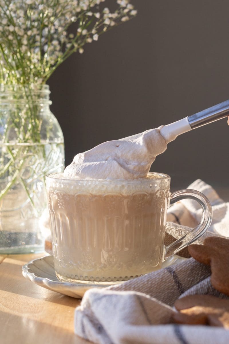 Putting the whipped cream on top of the cup.