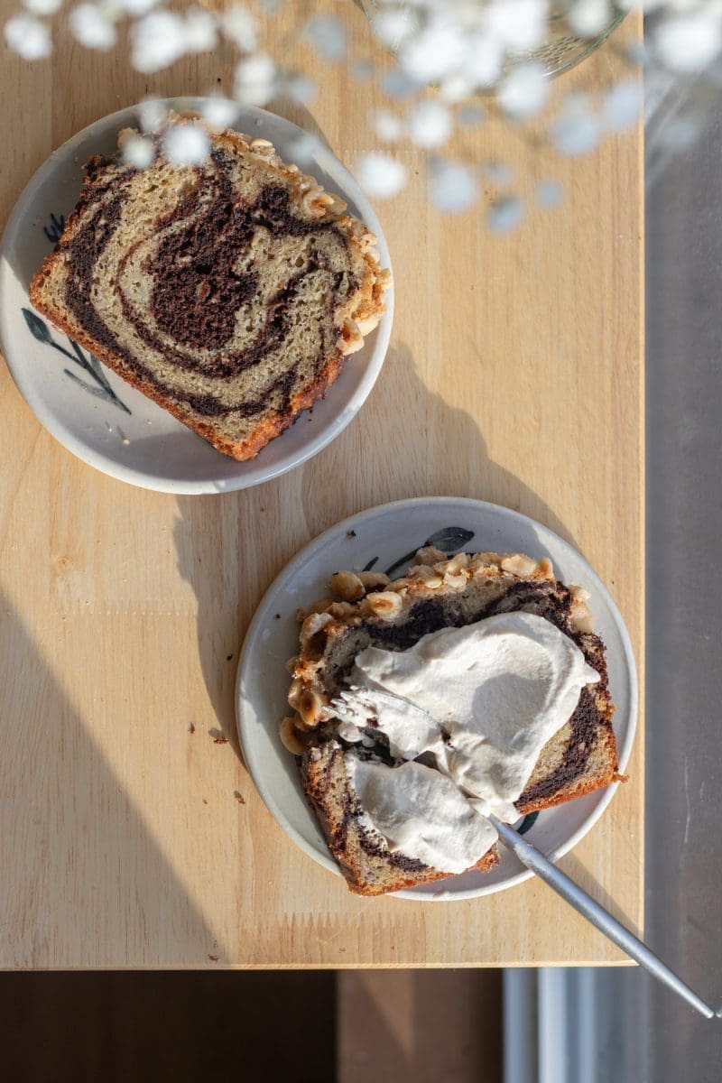 Two slices of chocolate marbled banana bread on plates.