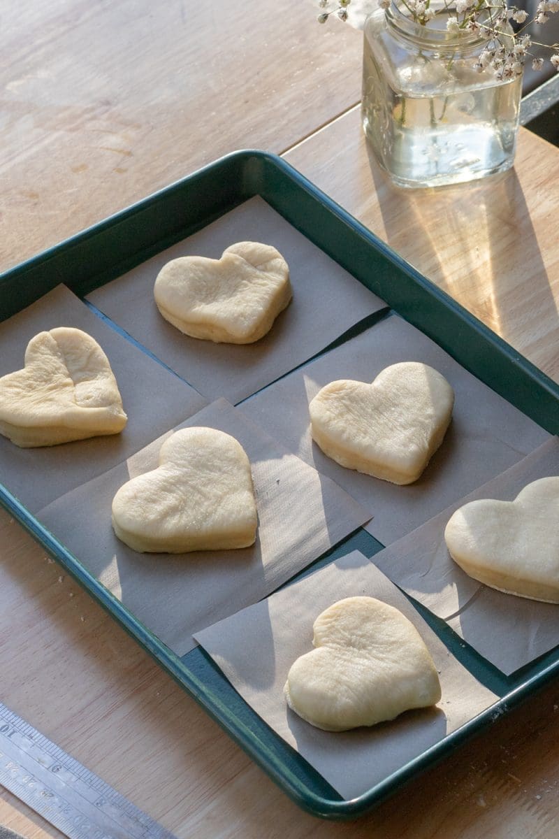 The cut-out heart donuts on parchment squares.