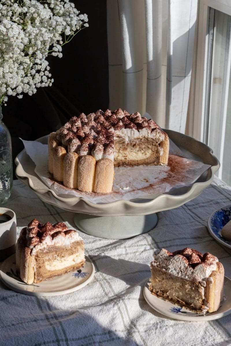 The tiramisu cheesecake on a cake stand, sliced.