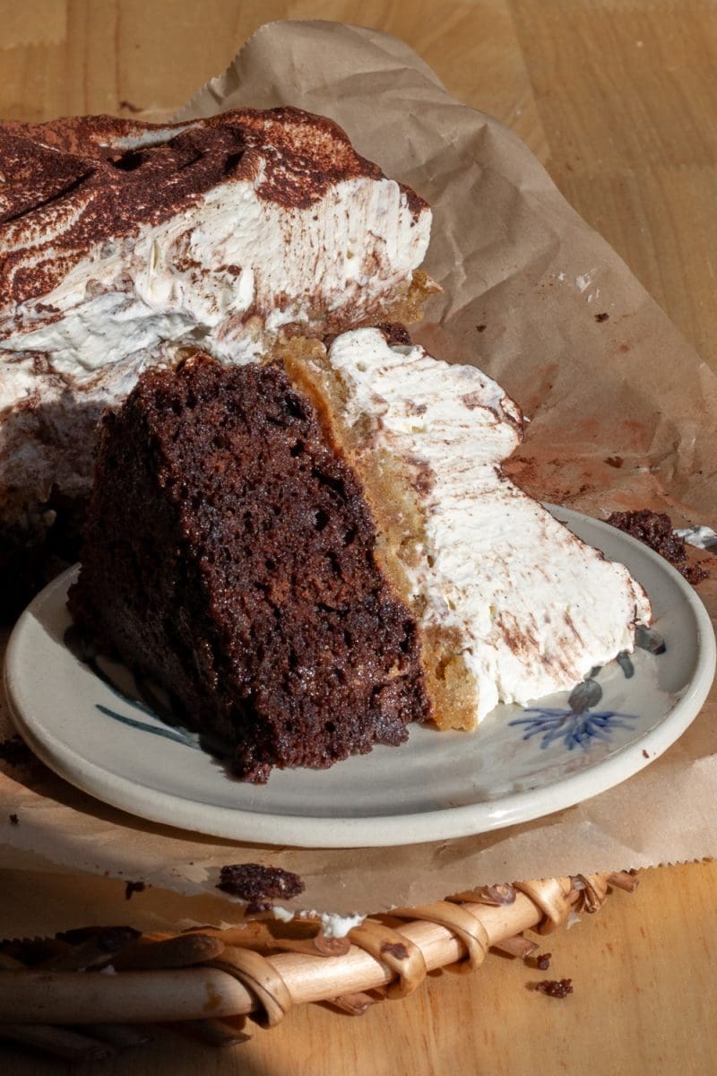 Close up slice of tiramisu chocolate cake on it's side on a plate.