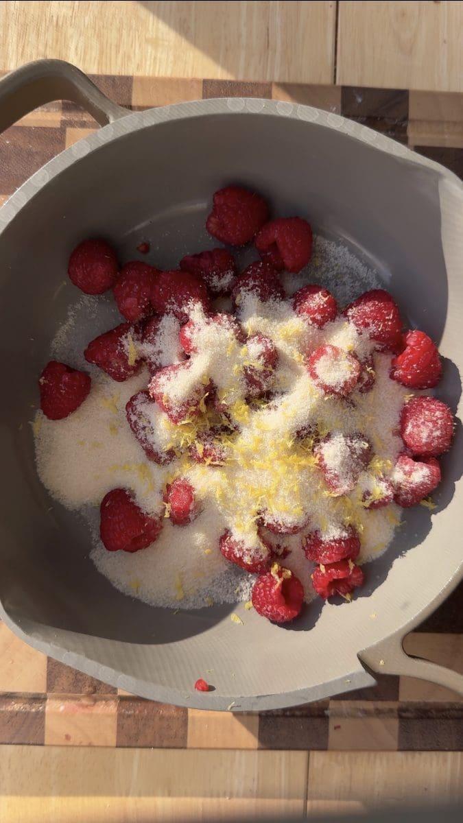 Raspberries, sugar, and lemon zest in a saucepan.