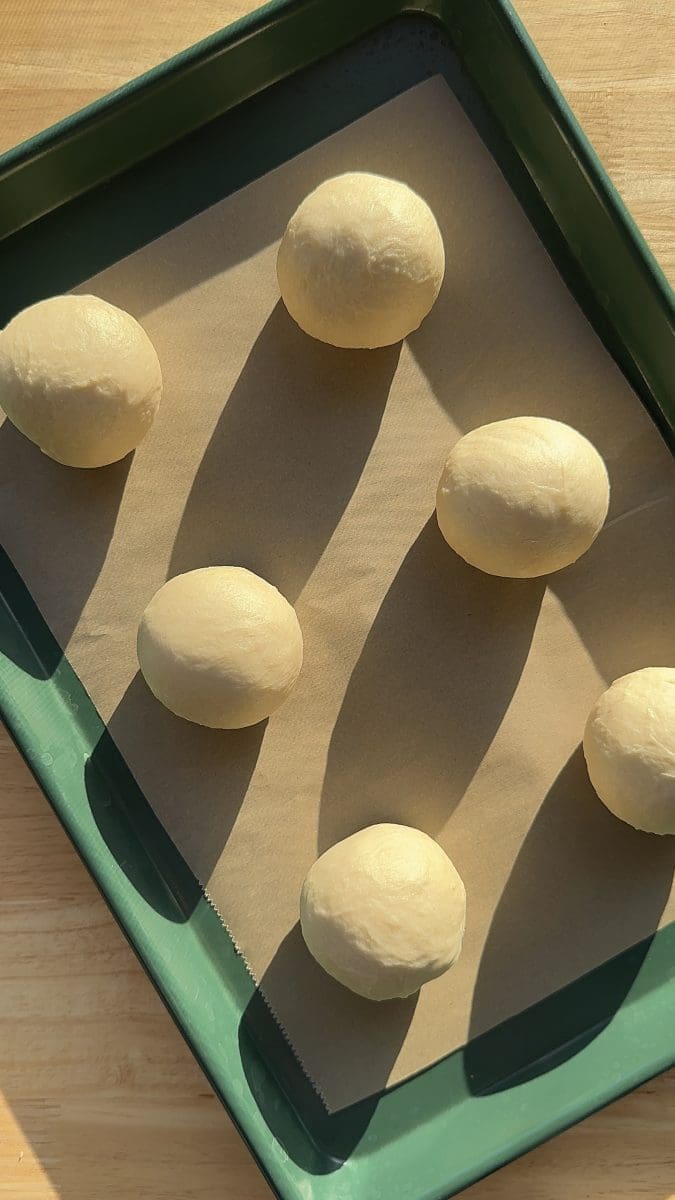 The dough pieces rolled up into balls and placed on a lined baking tray.