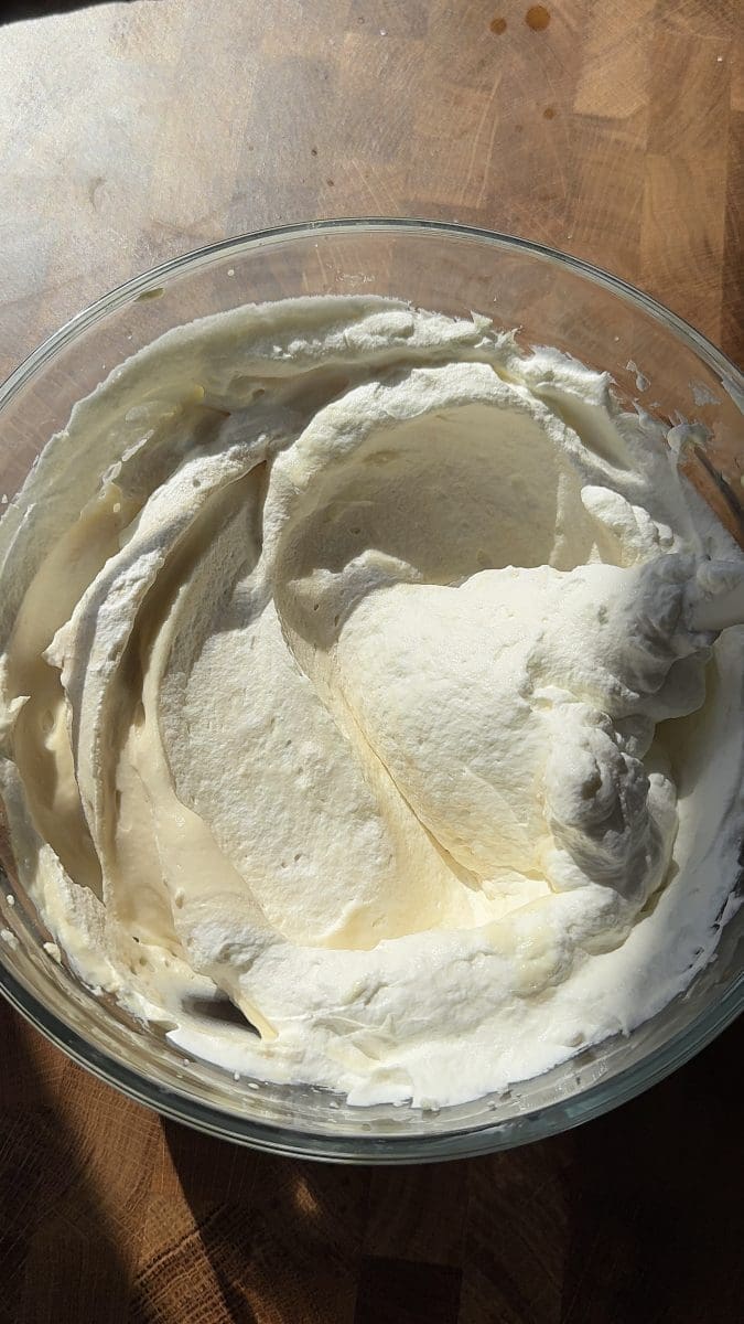 Folding whipped cream into the cheesecake batter.