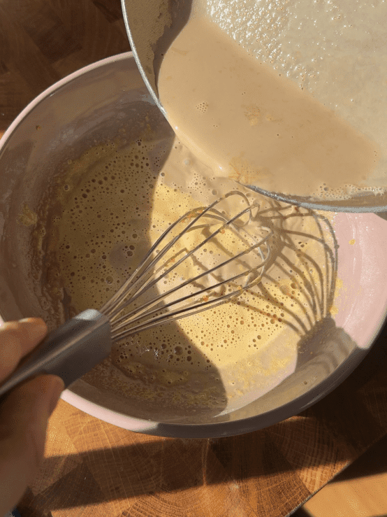 Whisking hot coffee milk into the egg mixture.