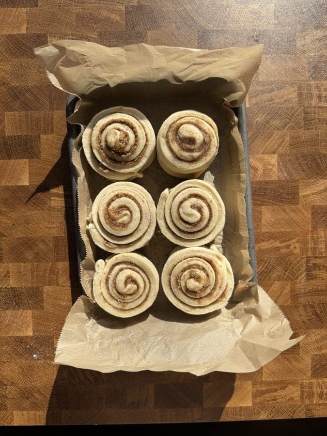 The cinnamon rolls on a parchment lined baking tray.
