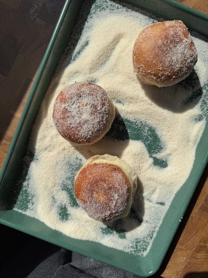 Coating the donuts in sugar.