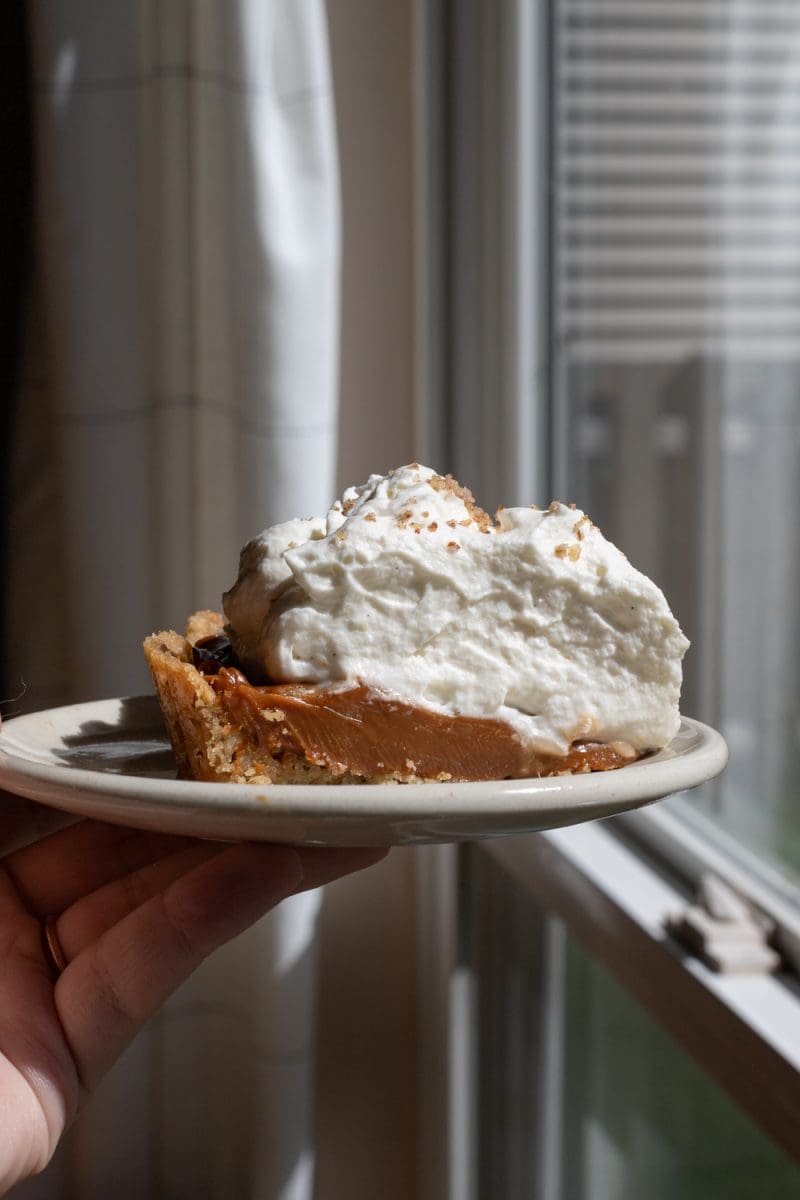Holding up a slice of the salted hazelnut banoffee pie.