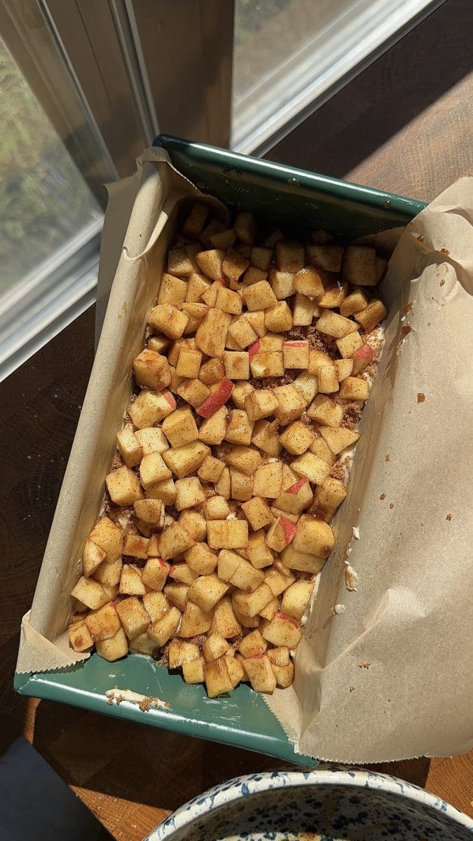 Apples over the loaf batter in a loaf pan.