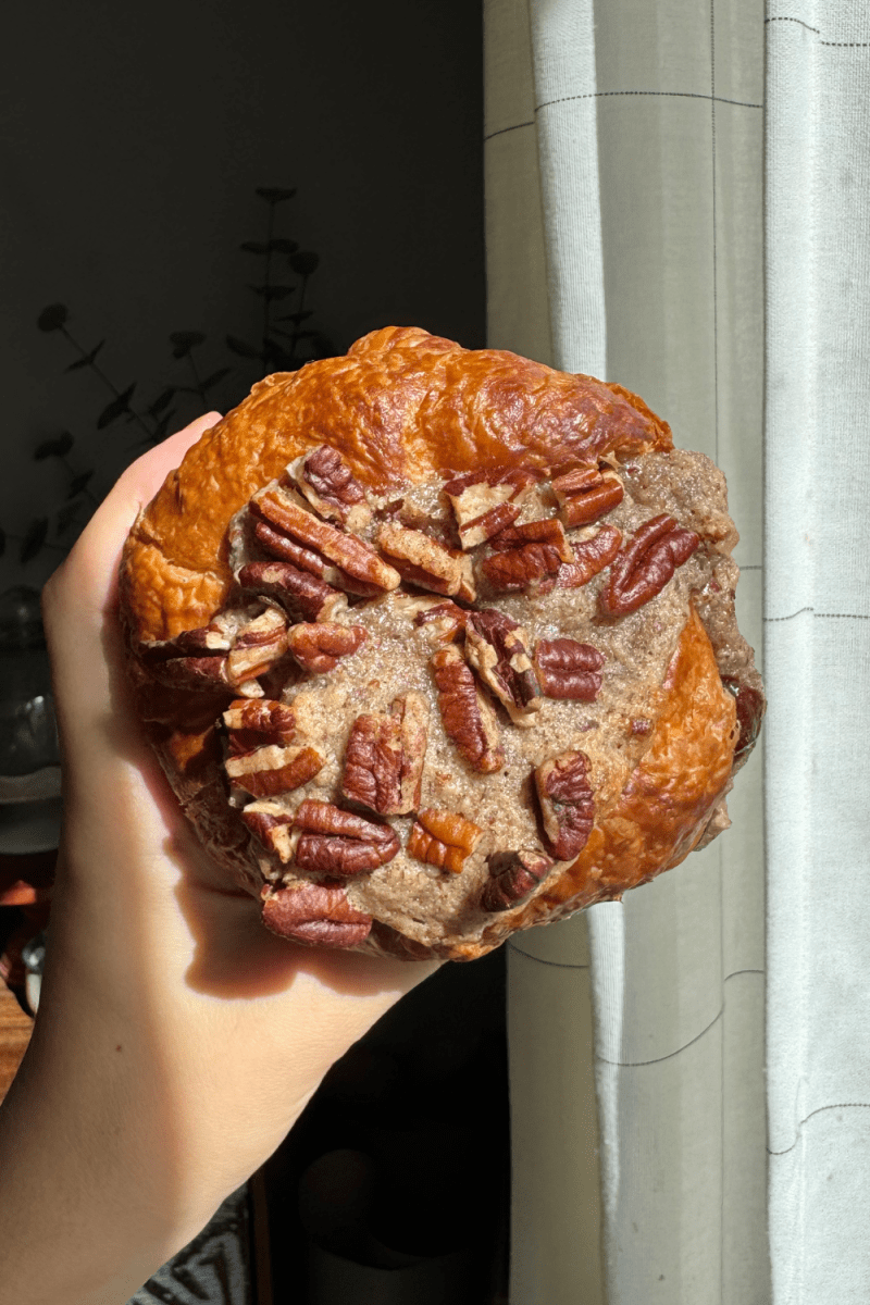 Holding up a pecan apple pie croissant