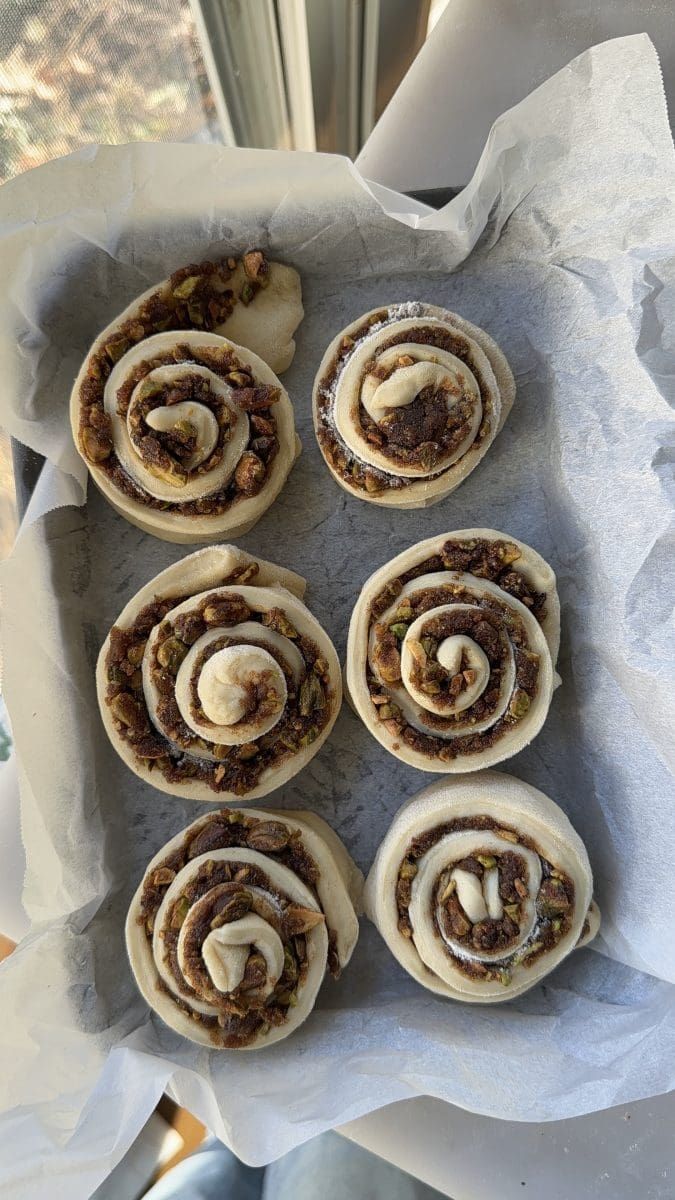 The pistachio cinnamon rolls rising in a baking tray.