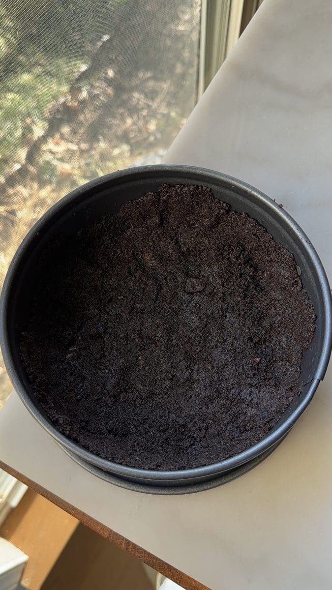Oreo crust pressed into a springform pan.