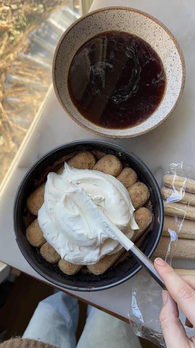 Spreading tiramisu filling over the ladyfingers.